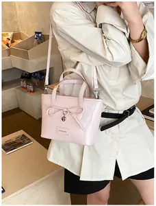 Close-up of pink patent leather tote with bow, heart pendant and metal brand logo