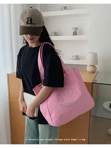 Detail of pink canvas tote bag featuring silver rivet shell pattern and wide handles