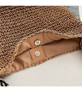 Detail of straw woven tote bag featuring magnetic snap closure and patterned strap