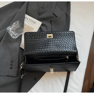 Dettaglio macro della borsa in pelle intrecciata nera con chiusura dorata e tasca interna