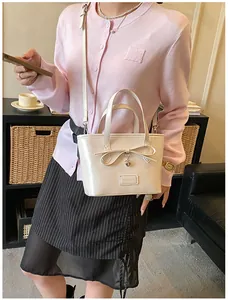 Detailed view of beige PU tote bag with bow decoration and heart charm on striped skirt