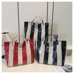 Close-up of waterproof striped tote bags in red, black, and navy with TOTE BAG logo