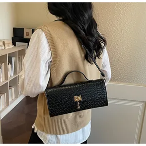 Dettaglio borsa a mano nera con trama intrecciata e chiusura a girello dorata sulla spalla