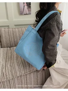Close-up of shell rhinestone pattern on blue canvas tote bag worn by a model