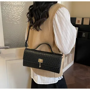 Dettaglio borsa in pelle goffrata nera con chiusura in metallo dorato e frange