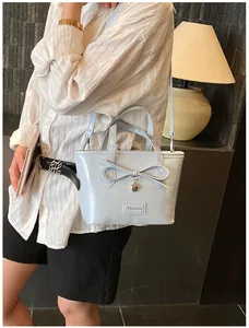 Detail of light blue leather tote bag featuring a bow decoration and heart charm