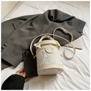 Size comparison of cream bucket bag with lace floral overlay and a smartphone