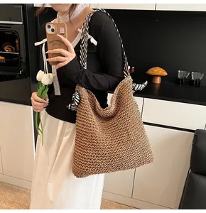 Detail of hand-woven straw tote with black and white striped bow shoulder straps