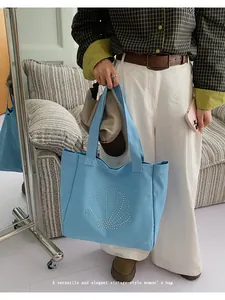 Close-up of a light blue canvas tote bag featuring a rhinestone shell design on the front