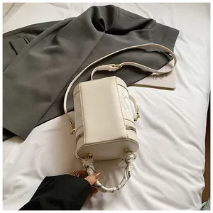 Close-up of off-white bucket bag with lace floral pattern and scarf wrapped handle