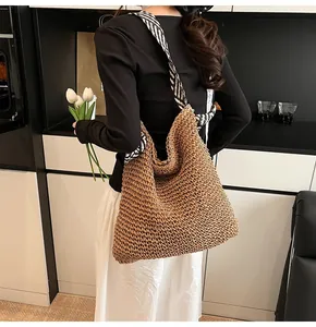 Detail of handwoven straw tote bag with black and white striped shoulder strap
