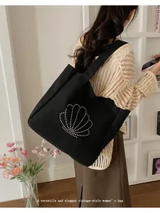 Detail of black canvas tote bag with metal beaded shell design and wide shoulder strap
