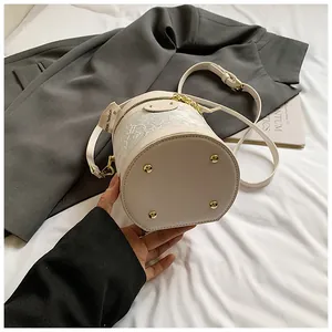 Detailed view of beige bucket bag with lace embroidery and golden anti-wear base studs