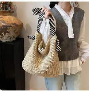Detailed texture of hand-woven straw shoulder bag with black and white striped ribbon handle