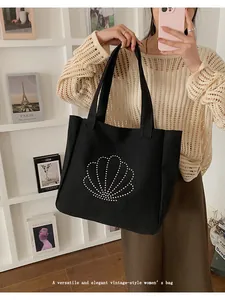 Detail of a black canvas tote bag featuring a studded scallop pattern for everyday use