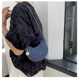 Detailansicht der blauen Denim-Halbmondtasche mit Steppmuster, Kette und Kamelien-Anhänger