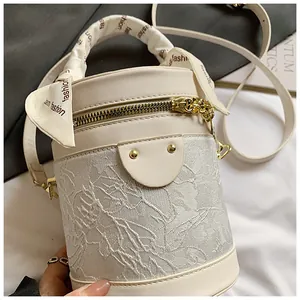 Detailed macro view of ivory bucket bag featuring lace floral patterns and silk scarf wrap