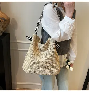Detail of hand-woven straw tote with black and white striped ribbon handle
