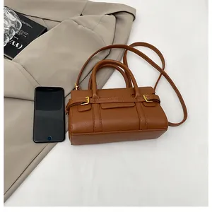 Détail d'un sac à main marron grainé avec boucle dorée et smartphone pour référence de taille