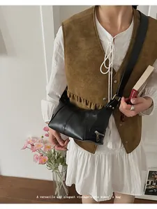 Detail of a black leather half-moon shoulder bag with a vintage aesthetic on a model