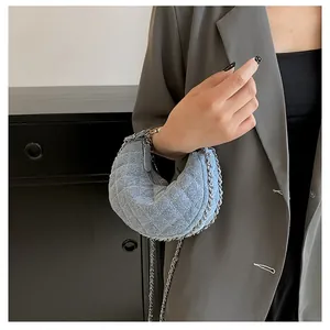 Nahaufnahme der hellblauen Denim-Halbmondtasche mit Rautensteppung und Silberkette