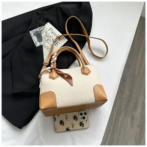 Détail du sac à main tissé beige avec bordure en cuir marron et foulard en soie décoratif