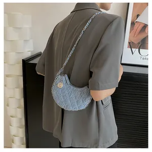 Detail der hellblauen Denim-Halbmondtasche mit Steppmuster und silberner Kette