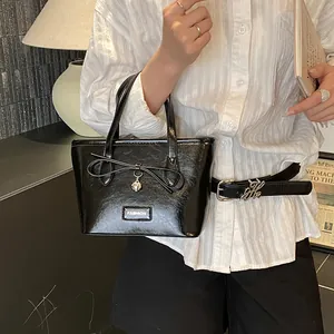 Chic black patent leather tote bag with bow detail and heart pendant in a lifestyle setting