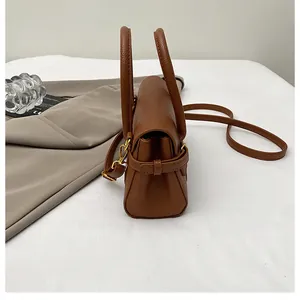 Détail d'un sac à main en cuir litchi caramel avec ferrures dorées et anses rondes