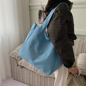 Light blue canvas tote bag with rhinestone shell design shown on shoulder for casual style