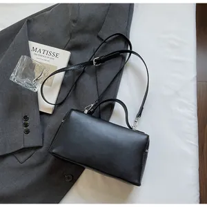 Detail view of black leather crossbody bag with silver hardware on a stylist background