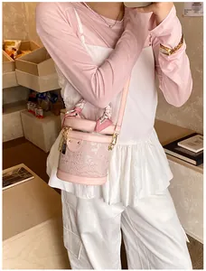 Detailed shot of a pink bucket bag with lace trim and silk scarf on the handle