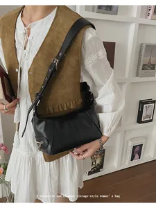 Detail of vintage black leather shoulder bag with silver zipper and buckle strap