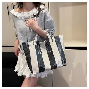 Detail of waterproof striped tote bag with comfortable handles held by a model