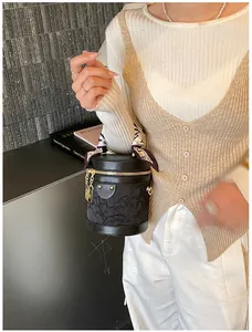 Detail of black bucket bag with rose texture and silk scarf wrapped handle