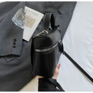 Close-up of a black leather handbag featuring silver zipper details and sleek handles