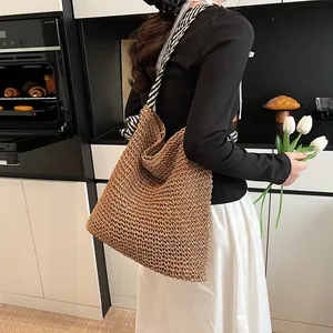 Large straw tote bag with black and white striped straps for beach travel and vacations