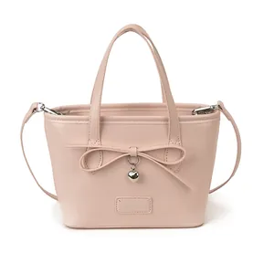 Pale pink tote bag with bow detail and silver heart pendant on a white background