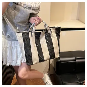 Detail of large black and white striped tote bag with sturdy handles and logo print