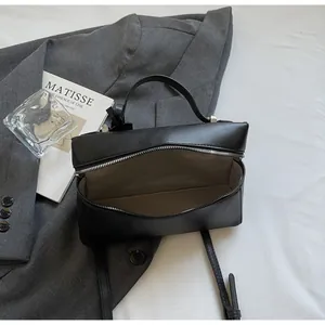 Detail view of the black leather handbag interior with zipper closure and khaki lining