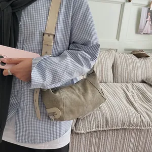 Olive green canvas hobo bag with off-white wide strap shown on model in home setting