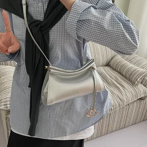 Sac bandoulière argenté métallisé à plis avec fine lanière et breloque dorée sur mannequin