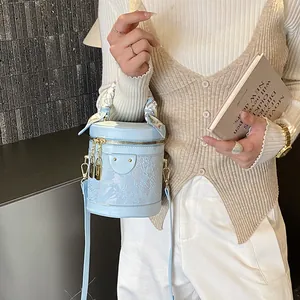 Light blue bucket bag with lace texture, silk scarf handle and gold hardware