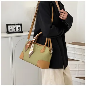 Détail du sac à main tissé vert avec garniture en cuir marron et foulard décoratif