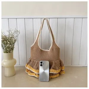 Size comparison of brown knitted tote bag with ruffles and a smartphone as reference