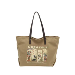 Khaki canvas tote bag with Anubis print and brown leather straps on white background
