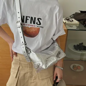 Silver metallic textured crossbody bag with eyelet strap shown on a model