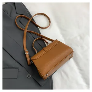 Détail d'un sac à main en cuir marron à motif litchi avec des rivets argentés