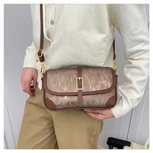 Detail of a vintage-style crossbody bag with contrast trim and metallic buckle on model