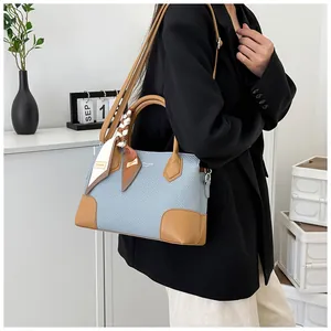 Détail du sac en tissu bleu avec garniture en cuir marron et poignée en foulard de soie